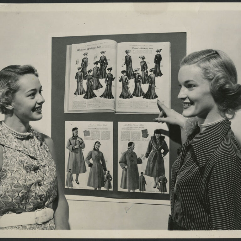 Deux_mannequins_regardent_la_mode_d’autrefois_dans_des_catalogues_de_Simpson’s